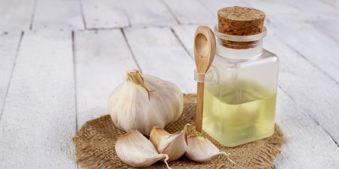 whole and chopped garlic next to a bottle of extract