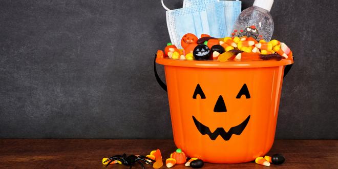 a trick or treat pail with sanitizer and a mask