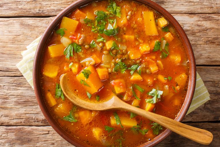 a bowl of stew with sweet potato, lentils, and leafy greens